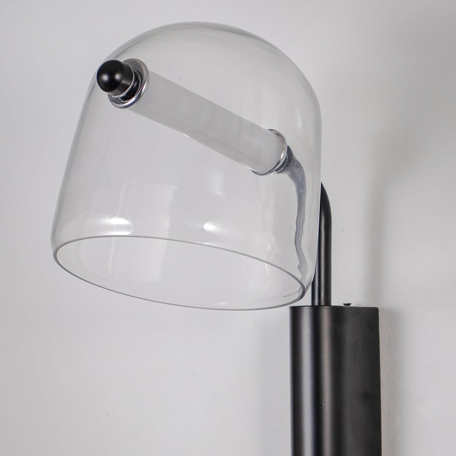 Closeup of clear glass wall lamp with black metal fixture showing minimalist design perfect for modern home wall lighting.