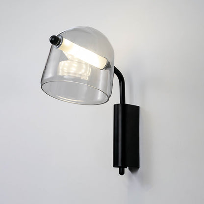 Modern clear glass wall light with black metal arm mounted on soft white wall background ideal for contemporary bedroom or living space lighting.