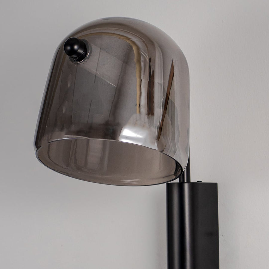 Closeup of smoked glass wall lamp with black metal fixture showing modern design details for stylish home wall lighting.