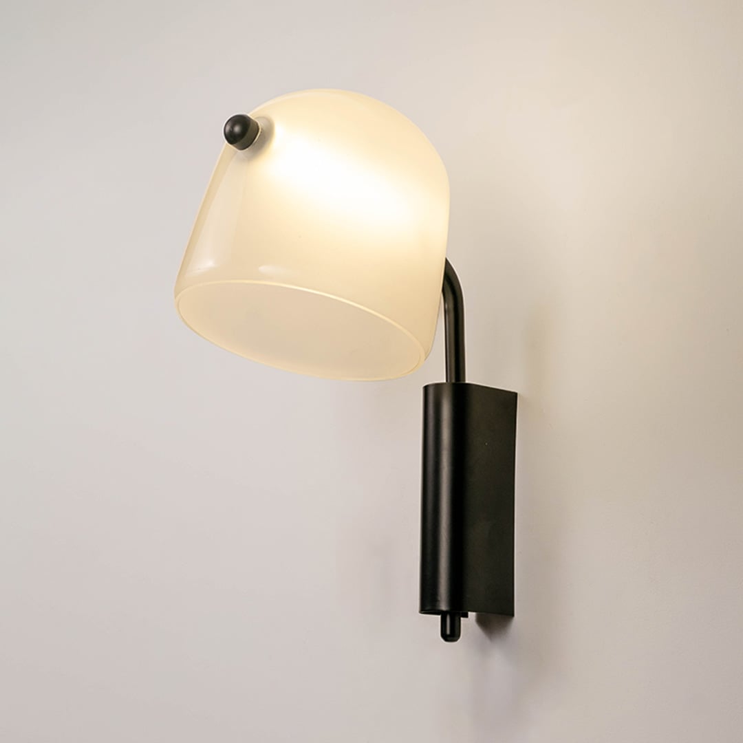 Frosted white glass wall light with black metal base glowing warm on white background elegant wall lamp for hallway decor.
