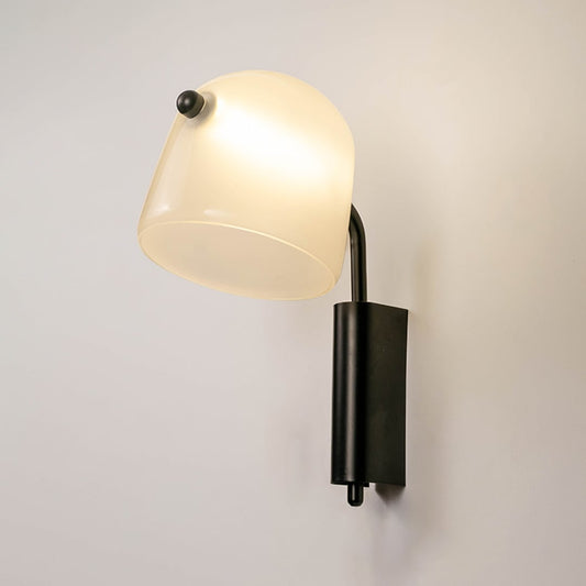 Frosted white glass wall light with black metal base glowing warm on white background elegant wall lamp for hallway decor.