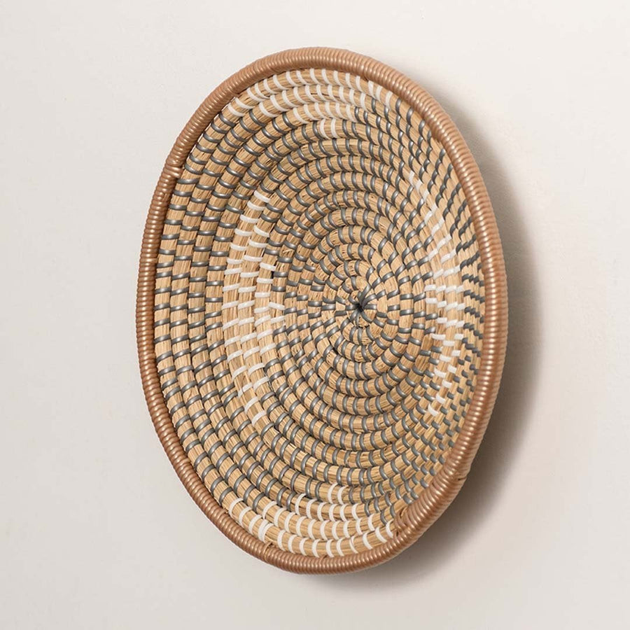 Side view of woven wall plate showing depth and curved rim made from durable handwoven natural fibers.