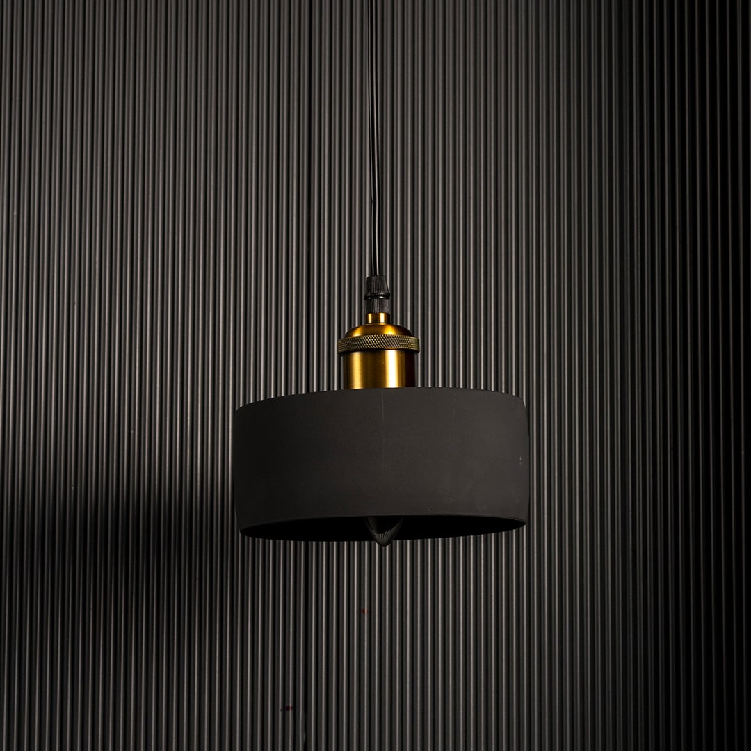 Black concrete pendant light turned off showcasing matte texture and brass accent for contemporary lighting design.