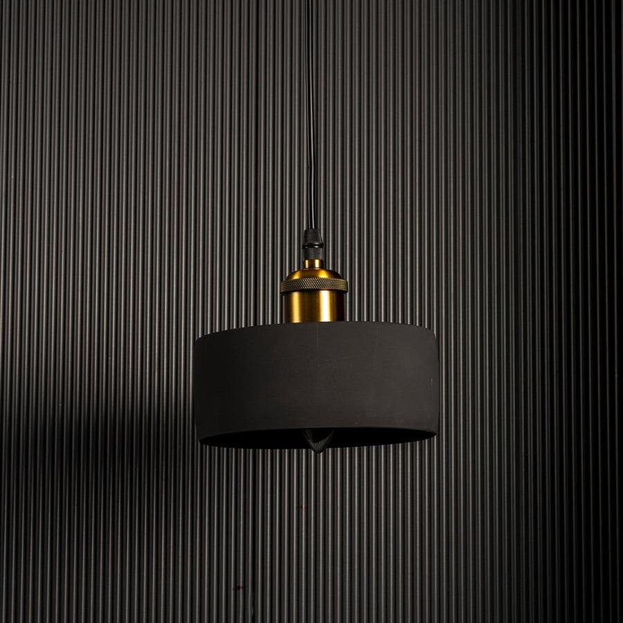 Black concrete pendant light turned off showcasing matte texture and brass accent for contemporary lighting design.
