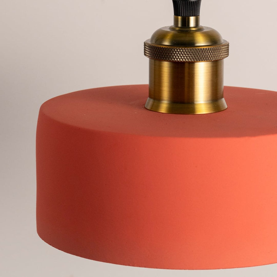 Matte terracotta pendant light featuring a clean cylindrical shade and brass holder displayed with the light off.
