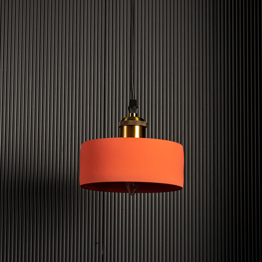 Contemporary pendant light featuring cylindrical orange metal shade and brass top creating warm focused lighting for interiors.