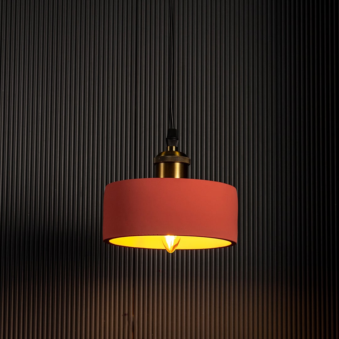Terracotta pendant lamp glowing warmly against a black background emphasizing its soft modern silhouette.
