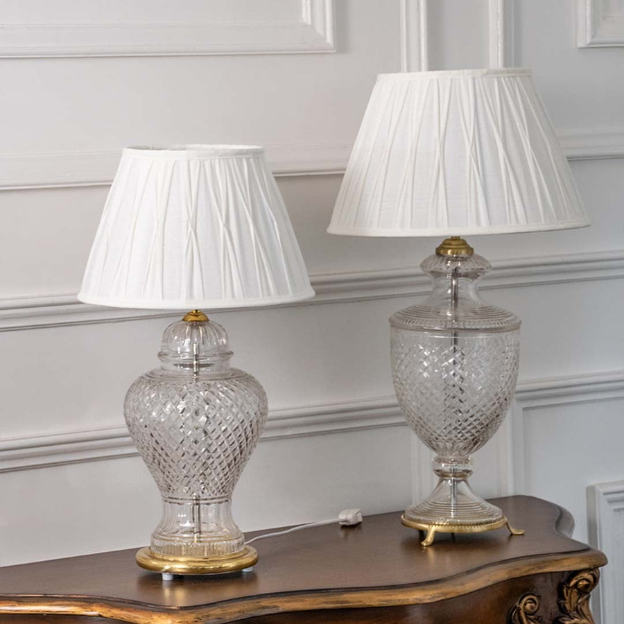Pair of crystal glass table lamps with pleated white shades turned off displayed on wooden console highlighting timeless elegance and modern charm.