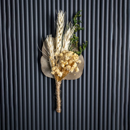 Decorative dried flower bouquet of wheat stalks white flowers and greenery tied with jute rope on black backdrop.
