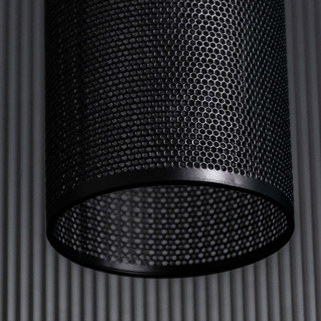 Closeup of black woven pendant light highlighting perforated texture layered weaving pattern and warm ambient light detail.