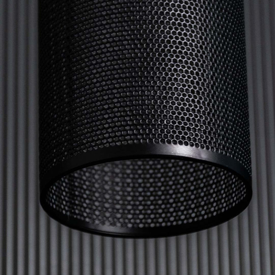 Closeup of black woven pendant light highlighting perforated texture layered weaving pattern and warm ambient light detail.