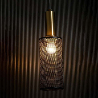 Gold pendant light glowing on black background highlighting warm illumination through perforated metal mesh industrial shade.