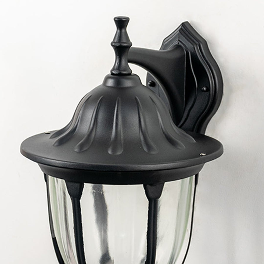 Closeup image of black metal outdoor wall light with textured top and ribbed glass for exterior decor.