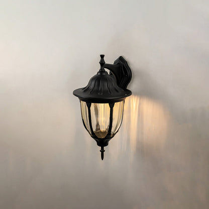 Black metal outdoor wall light on white background with clear ribbed glass shade for patio lighting decor.