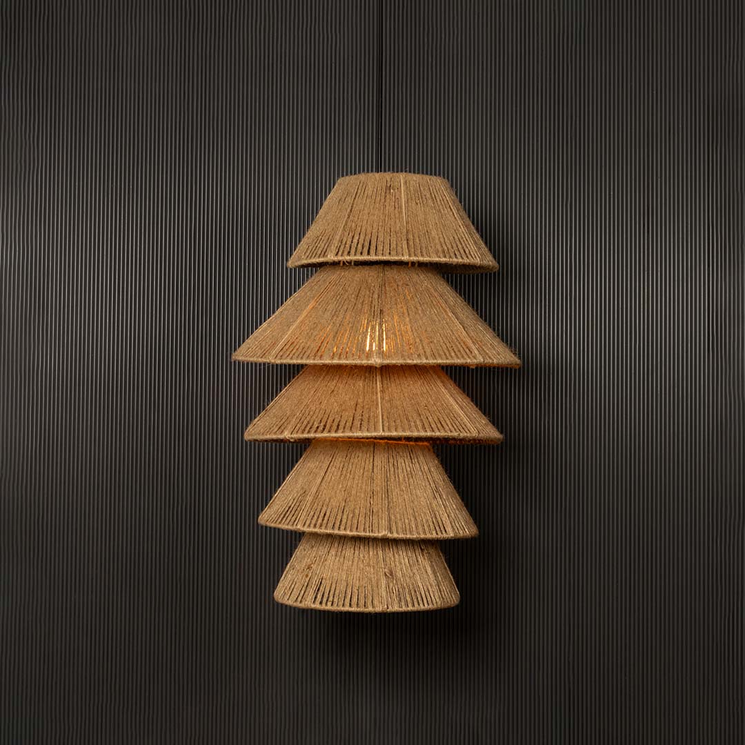 Handcrafted tiered jute pendant light against dark background emphasizing layered design and natural woven detailing.