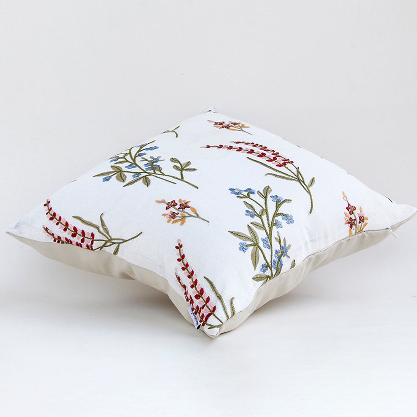 Floral embroidered cotton cushion displayed on a white background highlighting detailed stitched flowers and soft fabric texture ideal for home decor styling.