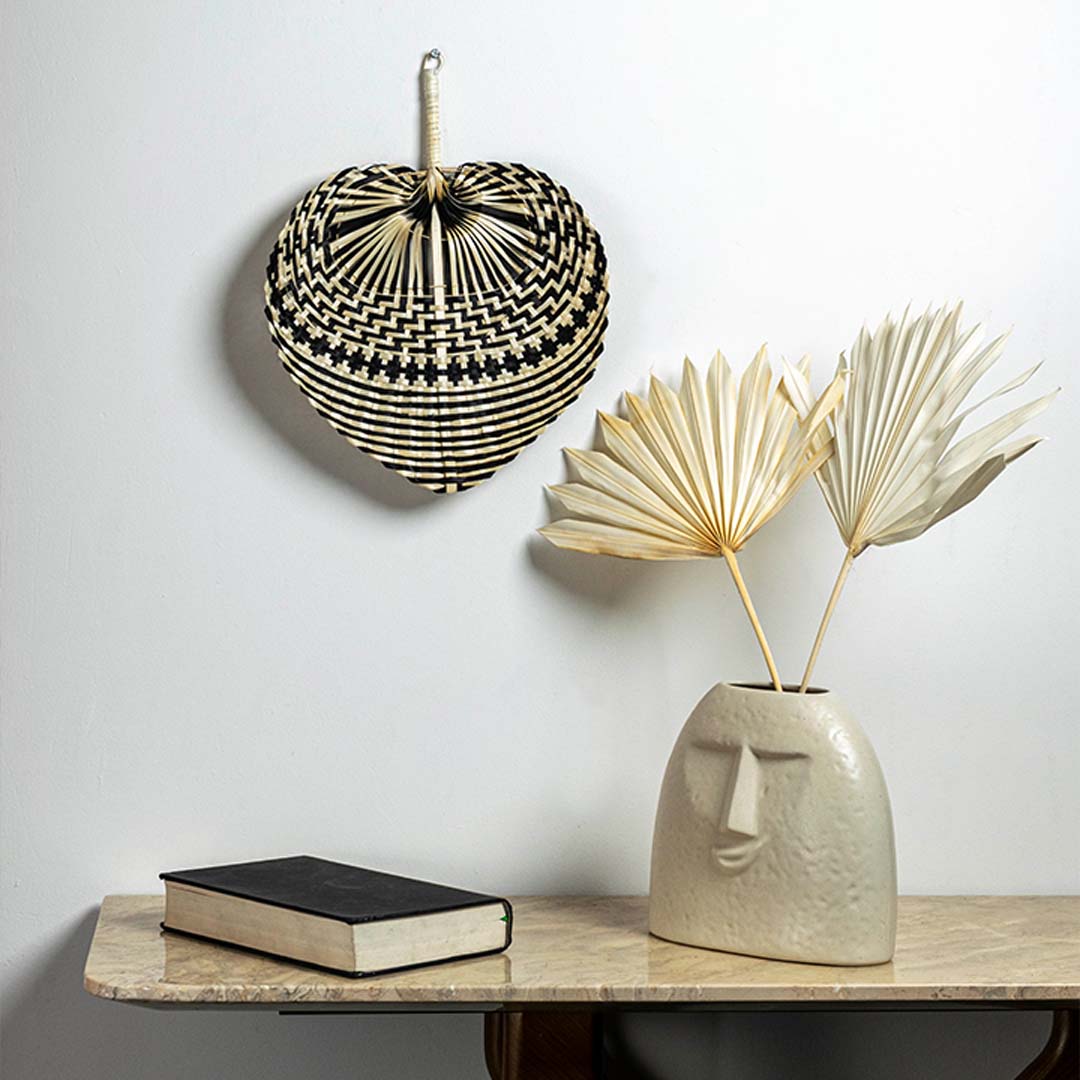Black and natural woven bamboo hanging basket displayed in bohemian interior creating stylish handcrafted storage solution.Retry