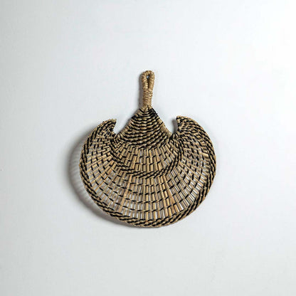 Round woven seagrass basket with black stripe pattern on white background showcasing handmade bohemian decorative wall piece.