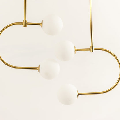 Modern ceiling chandelier light with curved gold rods holding four white globe shades arranged in a balanced flowing design against a light background.