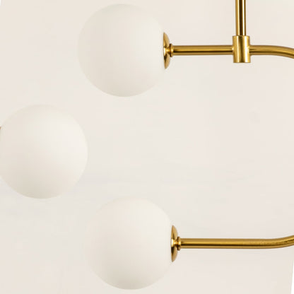 Close up of a modern ceiling chandelier light with gold rods supporting three round white frosted globes arranged in a smooth curved layout.