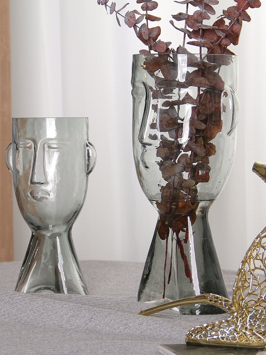 Set of face shaped glass vases in clear finish styled with dry branches modern artistic decor for living room and tabletop styling.