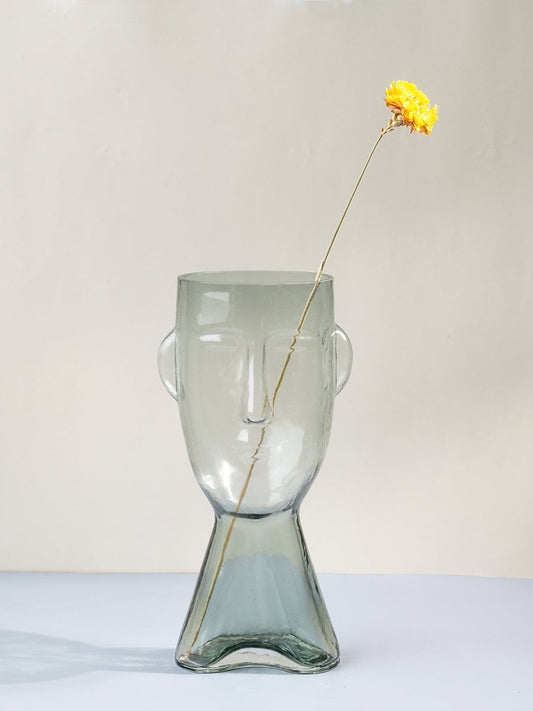 Clear glass vase in abstract human face shape tall decorative modern design light on white background for contemporary interiors.