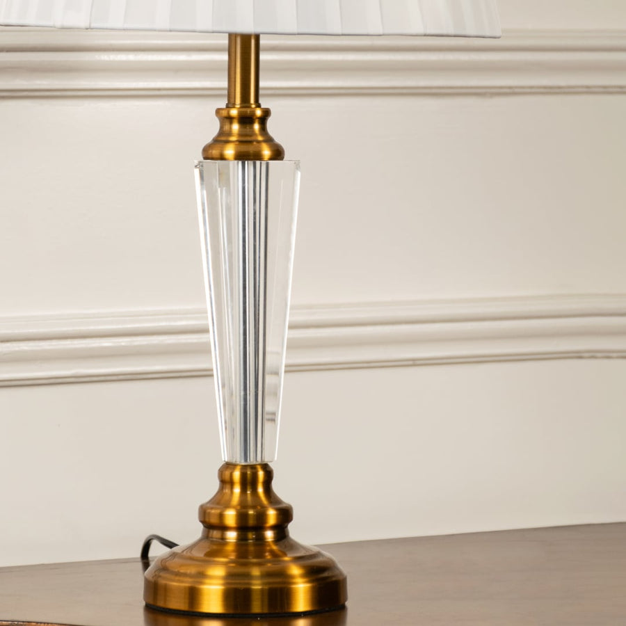 Closeup of crystal and gold lamp base with white pleated fabric shade highlighting elegant finish and details table lamp.