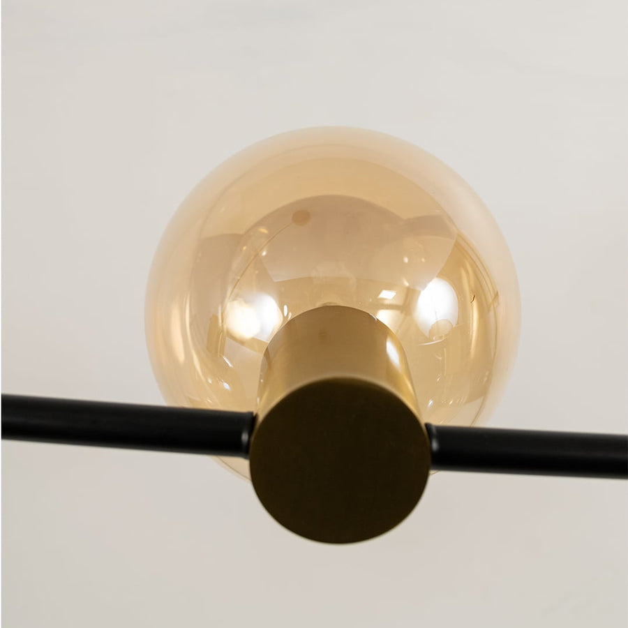Close view of amber glass chandelier showing sleek black rod polished fittings and smooth glass globes for modern indoor decor.