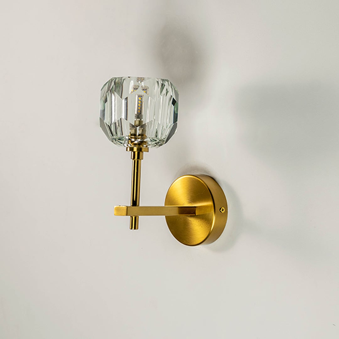 Crystal glass and brass wall light turned off on white wall showcasing modern luxury home lighting design.