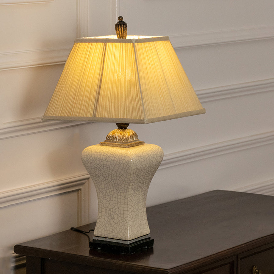 White textured ceramic table lamp with pleated fabric shade offering warm classic decor and ambient lighting indoors.