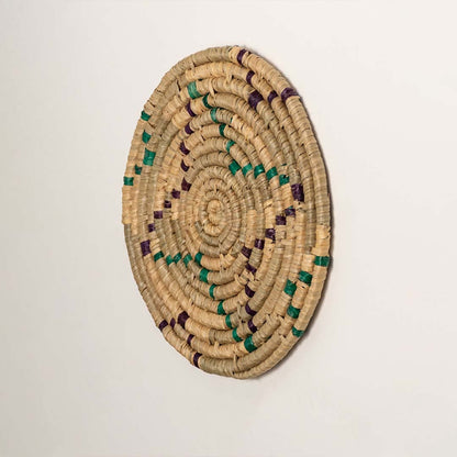 A side profile of the teal mustard and natural rattan wall decor plate showing its raised rim and detailed weaving for warm artisan inspired interior styling.