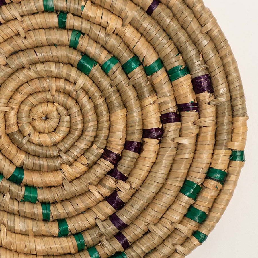 A closeup view of the teal mustard and natural rattan wall decor plate showing its detailed sunburst inspired weave and textured handcrafted pattern for vibrant decor styling.