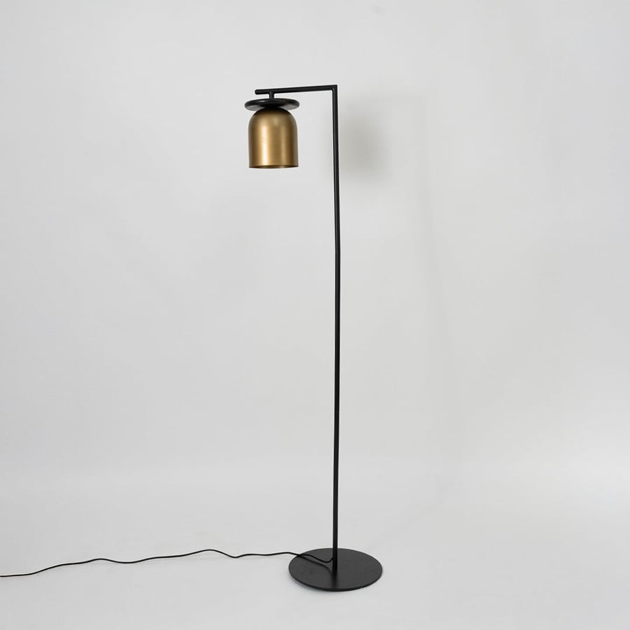Closeup of gold metallic lamp shade with black top disc detail on sleek black rod frame for modern interior decor.