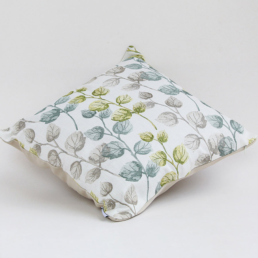 Soft cotton cushion cover with green and grey botanical motifs displayed at an angle offering a subtle nature inspired décor element with a breathable gentle and skin friendly fabric finish.
