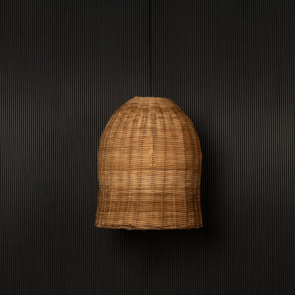 Dome-shaped rattan pendant light with handwoven bamboo shade turned on glowing softly against black background.