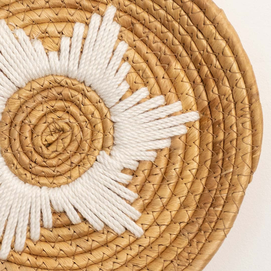 Detailed closeup view of the tight coil weaving and white stitched star center on the natural seagrass wall basket surface quality.