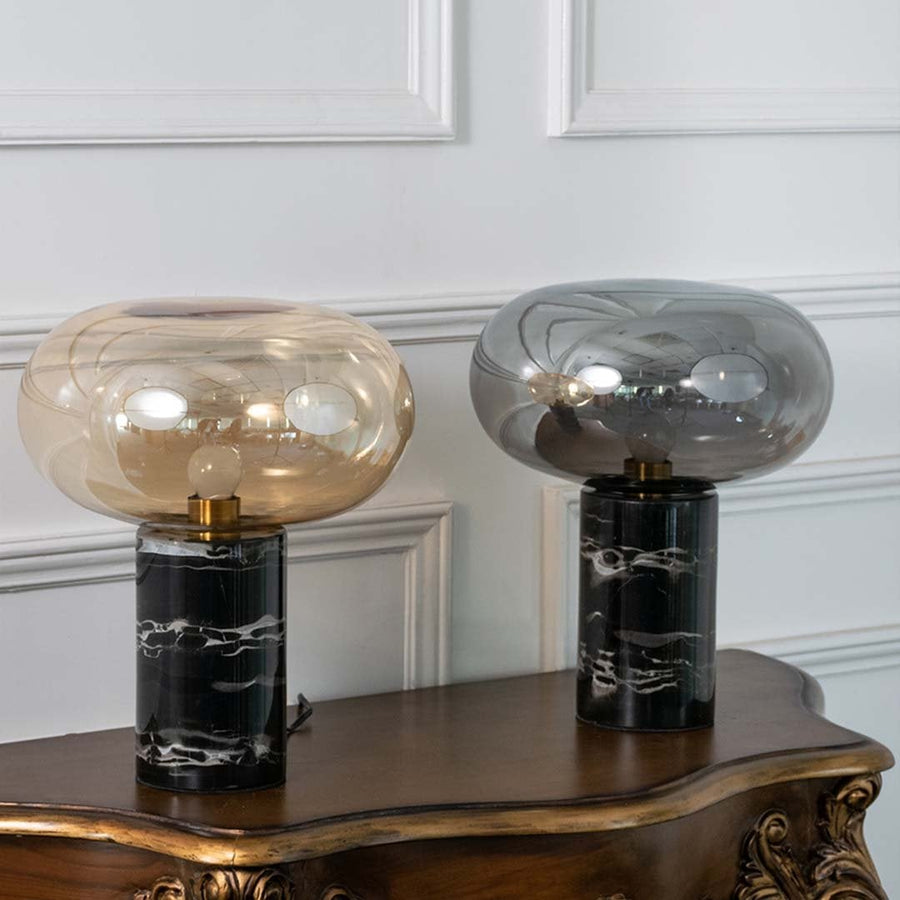 Collection of amber glass table lamps with black marble bases displayed on white background showcasing their sleek modern and artistic appeal.