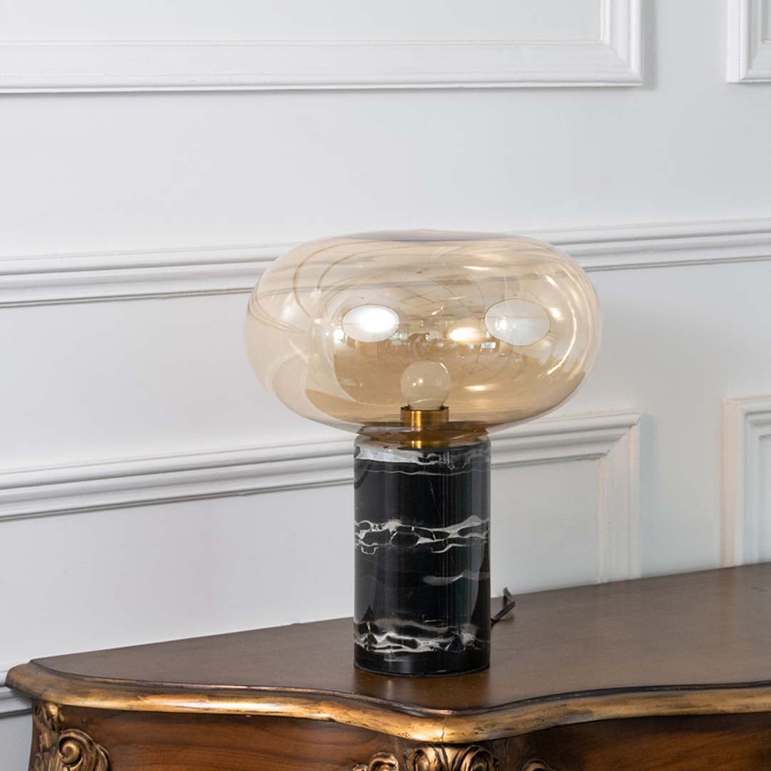 Contemporary black marble and amber glass table lamp displayed on white background with light turned off showcasing its sleek design.