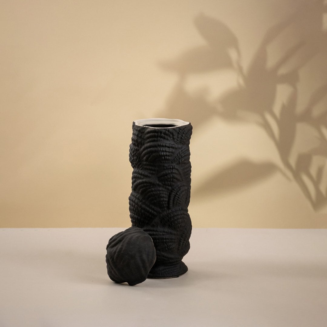 Modern handcrafted black ceramic vase with unique spiral pattern shown on white background perfect for minimalist interior decoration.