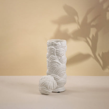 White ceramic vase illuminated gently on white background emphasizing its delicate grooves and handcrafted ceramic design.