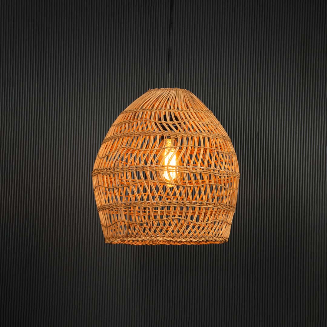 Open weave rattan pendant light with handwoven bamboo shade turned on glowing softly against plain black background.