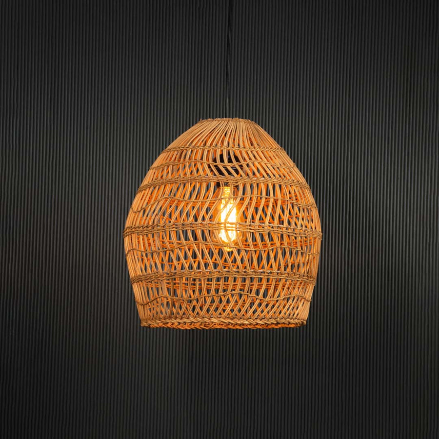Open weave rattan pendant light with handwoven bamboo shade turned on glowing softly against plain black background.
