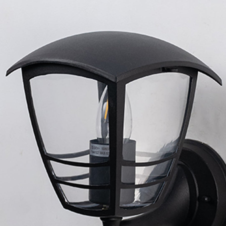 Black metal outdoor wall light closeup image with clear curved glass panels and protective wire cage for porch decor.