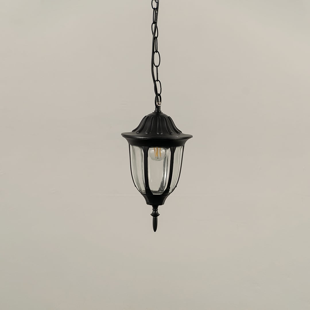 Black metal hanging lantern on white background with light off showing clear curved glass panels and decorative top finial perfect for traditional outdoor decor.