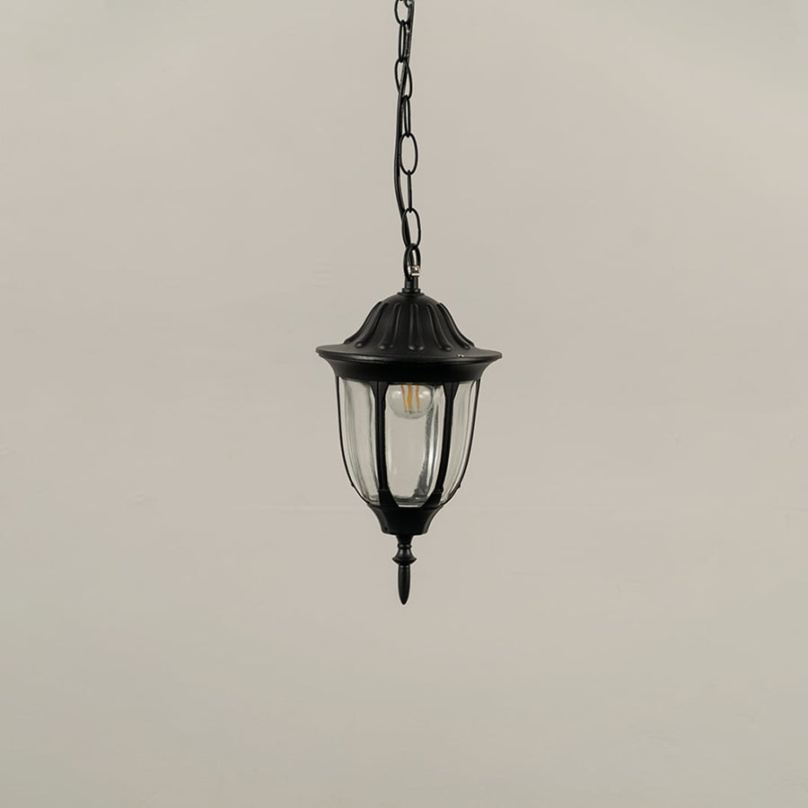 Black metal hanging lantern on white background with light off showing clear curved glass panels and decorative top finial perfect for traditional outdoor decor.