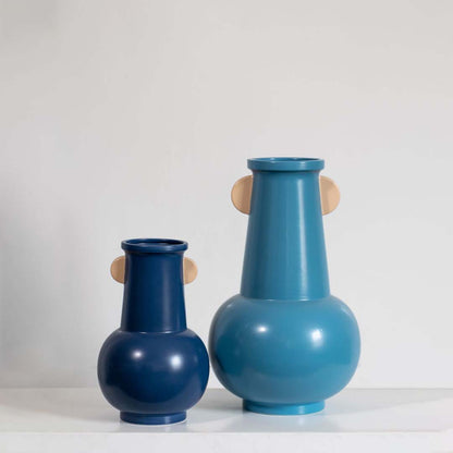 A collection display featuring a modern blue vase with rounded base highlighting its sculptural form and decorative appeal.