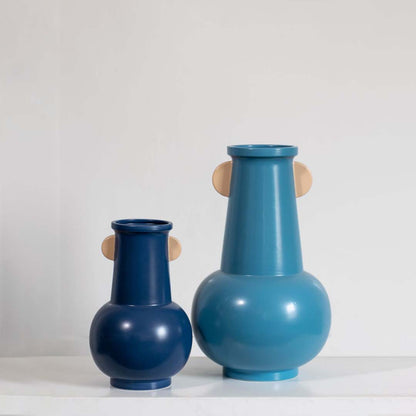 Blue sculptural metal vase grouped with contemporary decor pieces creating a stylish cohesive modern display.