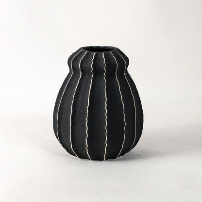 Minimal Noir ceramic vase on white background accentuating its curvy silhouette and artistic white-lined texture.