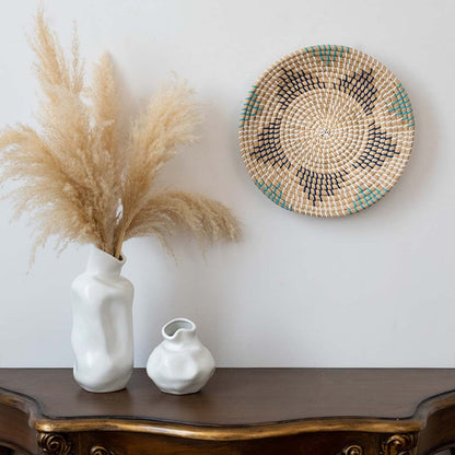 Handwoven wall basket decor in natural beige with blue and black pattern styled above console table for boho wall.