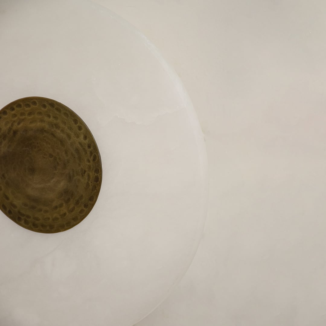 Closeup of white marble and textured gold metal wall light for premium modern decor styling spaces.